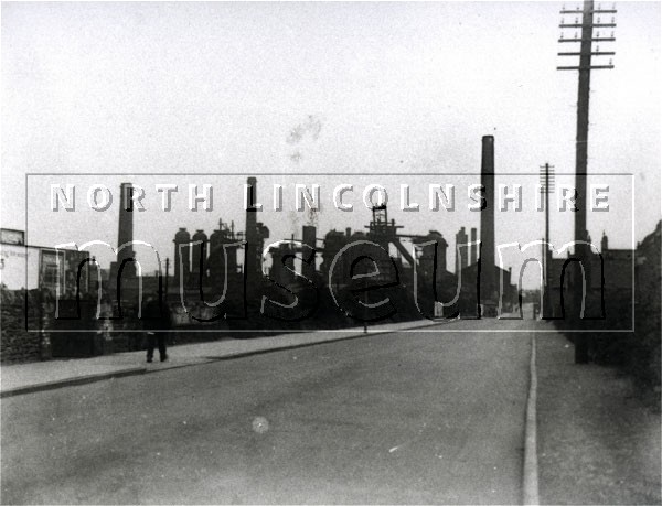 Looking south along Station Road, Scunthorpe, now High Street East, with the former railway goods station on the left and the blast-furnaces of Appleby-Frodingham Steelworks behind. Circa 1920's before 1928 	