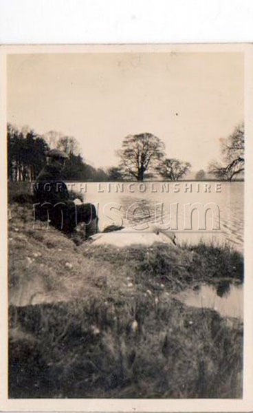 Normanby Hall Estate gamekeeper, Steven Green, sitting next to a swan at the lake in Normanby Park, c.1950